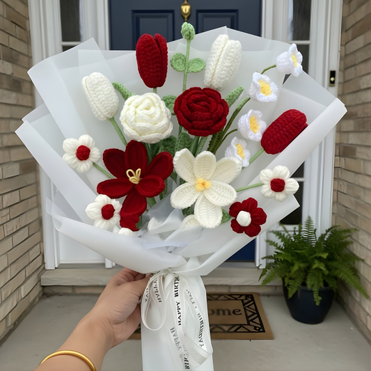 Bouquet of red and white flowers made of yarn held by a person in front of a door.