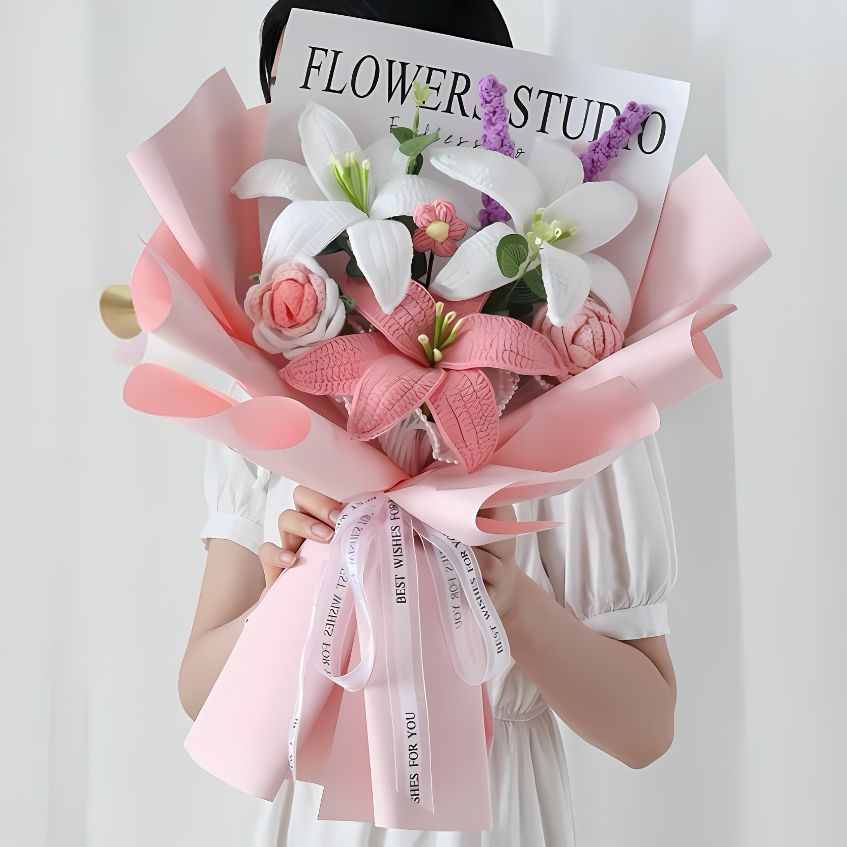 Bouquet of flowers with pink ribbons held by a person wearing a 'Flower Studio' shirt.