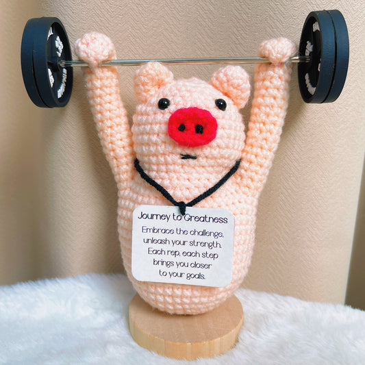 Figurinha de Porco Feita à Mão em Crochê - "Viagem à Grandeza" - Mensagem Personalizada e Customizável Inspiracional Aceite o Desafio e Desbrave a Força com Acessório de Haltere e Base de Madeira Presente para Aniversário, Formatura ou Celebração