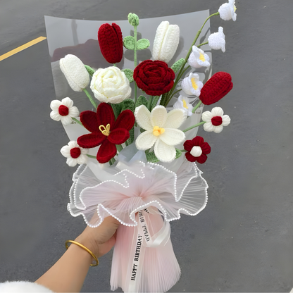 Bouquet of red, white, and green flowers held by a person against a dark background