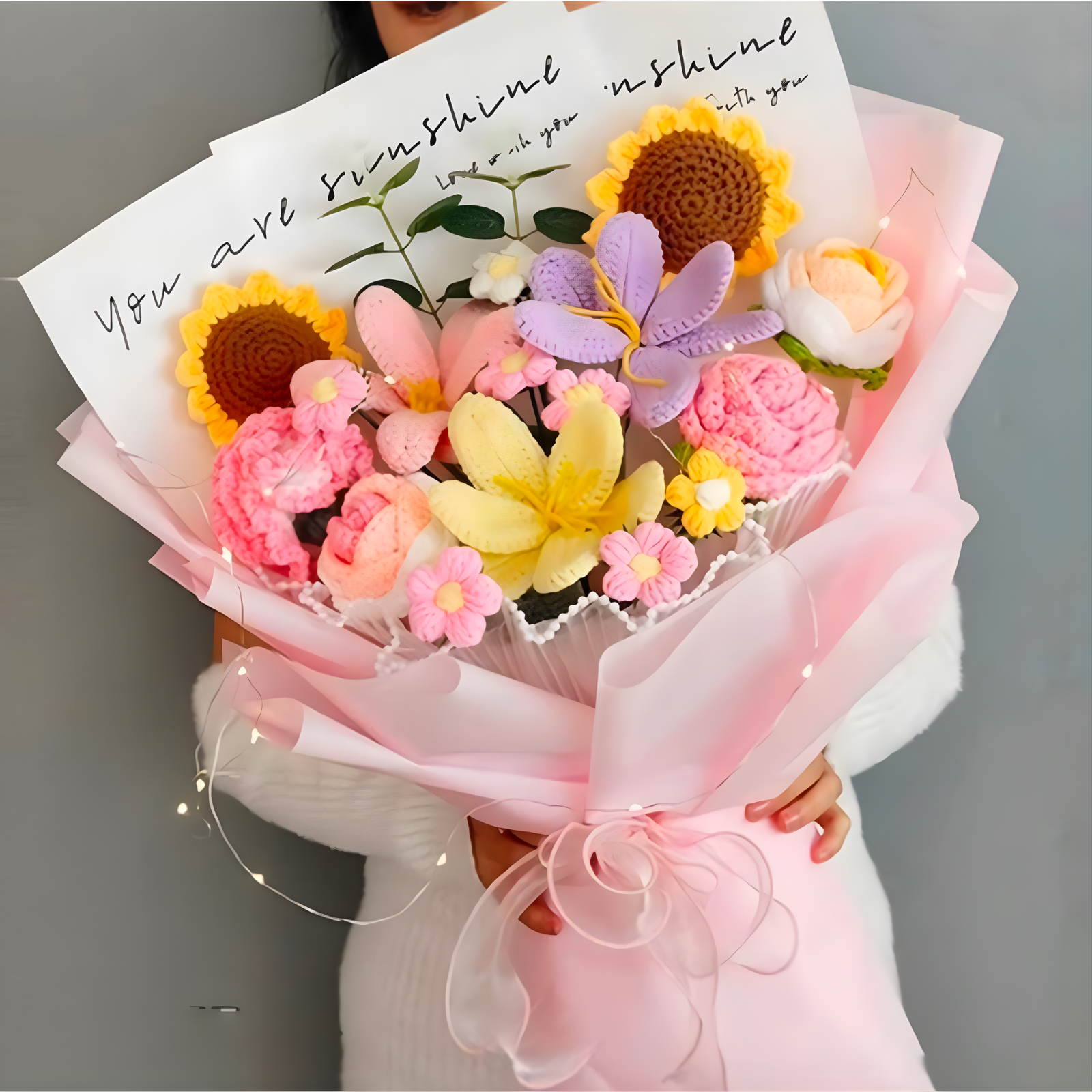 Bouquet of colorful crocheted flowers with a card reading 'You are my sunshine' held by a person.