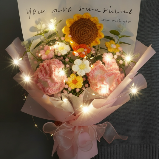 A crocheted bouquet imitating sunflowers, carnations, and other flowers, wrapped in pink paper with a card that reads 'You are sunshine. Love always.