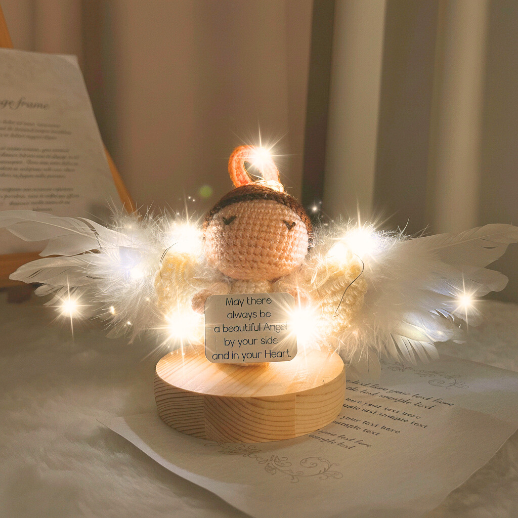 Decorative angel figurine with lights and a quote card on a soft surface.