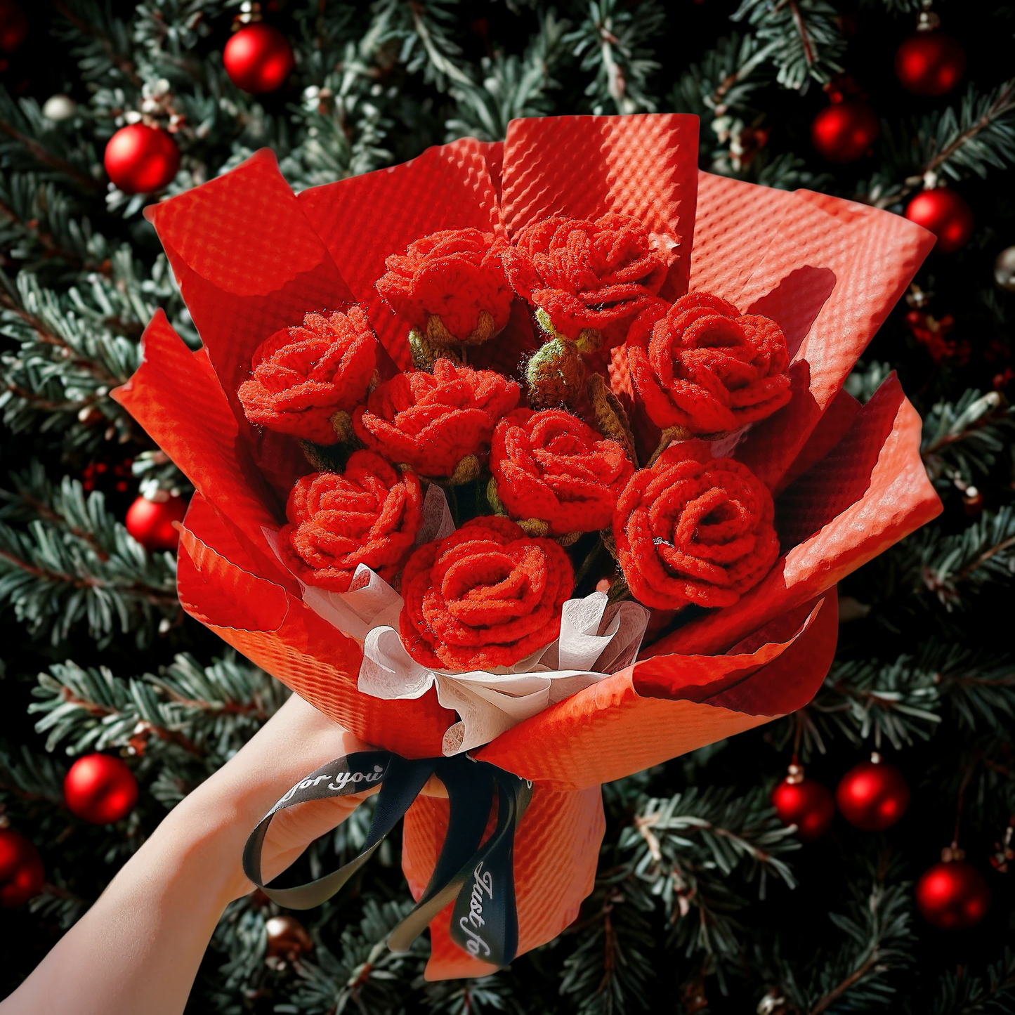 Bouquet of red flowers wrapped in red paper against a Christmas tree background