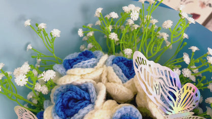 Bouquet de Roses Gradientes de Branco a Azul Congeladas com Espinhas de Bebê Branco e Acentos Vibrantes de Borboletas Coloridas, Belamente Embalado em Papéis Azul Claro e Escuro, Ideal para Celebrações como de uma Princesa