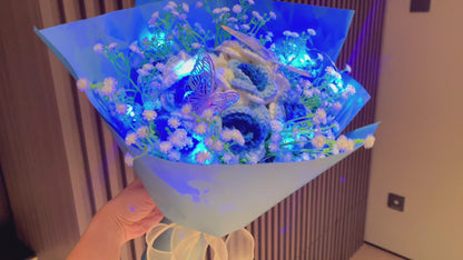 Bouquet de Roses Gradientes de Branco a Azul Congeladas com Espinhas de Bebê Branco e Acentos Vibrantes de Borboletas Coloridas, Belamente Embalado em Papéis Azul Claro e Escuro, Ideal para Celebrações como de uma Princesa