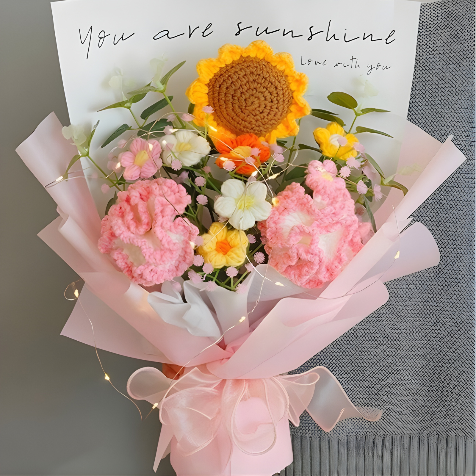 Bouquet of flowers with a crochet sunflower and pink flowers, accompanied by a card with 'You are sunshine' text.